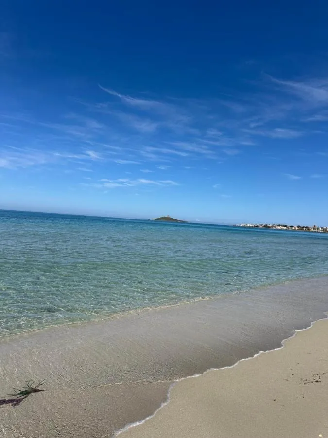 Spiaggia di sabbia chiara con acqua trasparente e un isolotto all'orizzonte